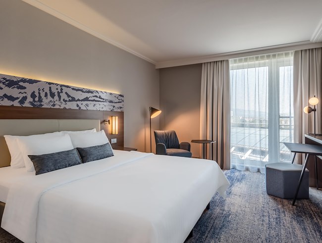 Hotelzimmer mit King-Bett, Schreibtisch und Sessel im Courtyard by Marriott Linz